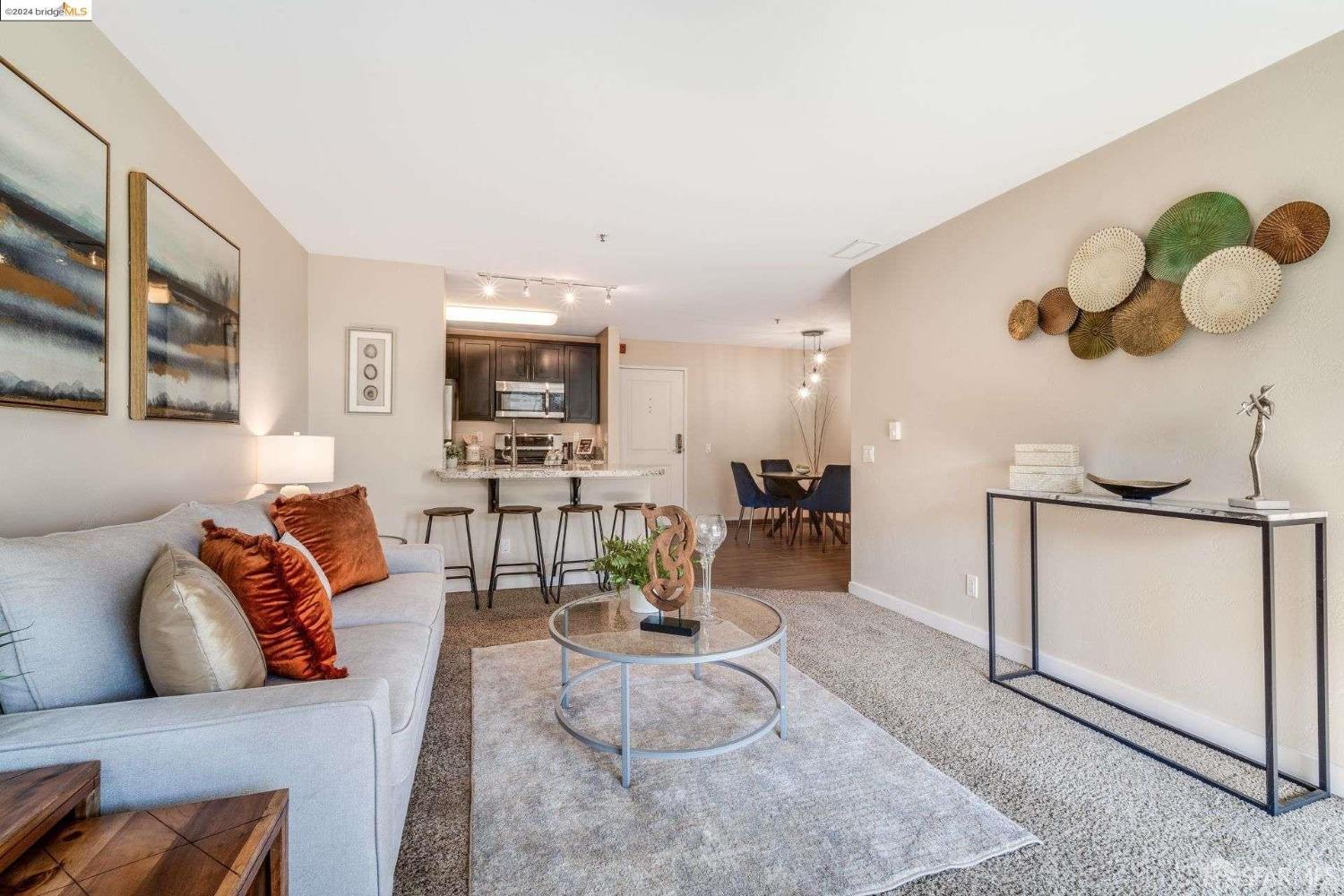 a living room with furniture kitchen view and a wooden floor