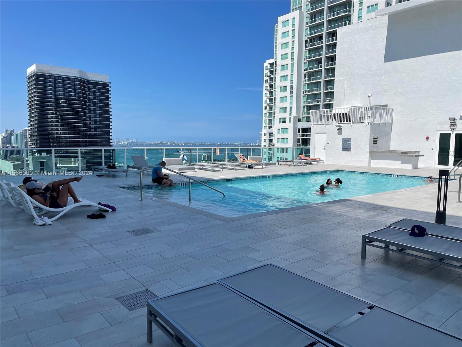 a view of a swimming pool with lawn chairs and a barbeque