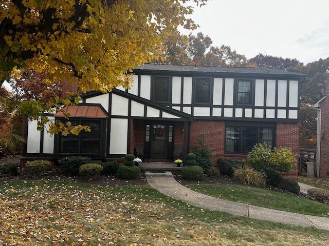 a view of a house with a small yard and a large tree