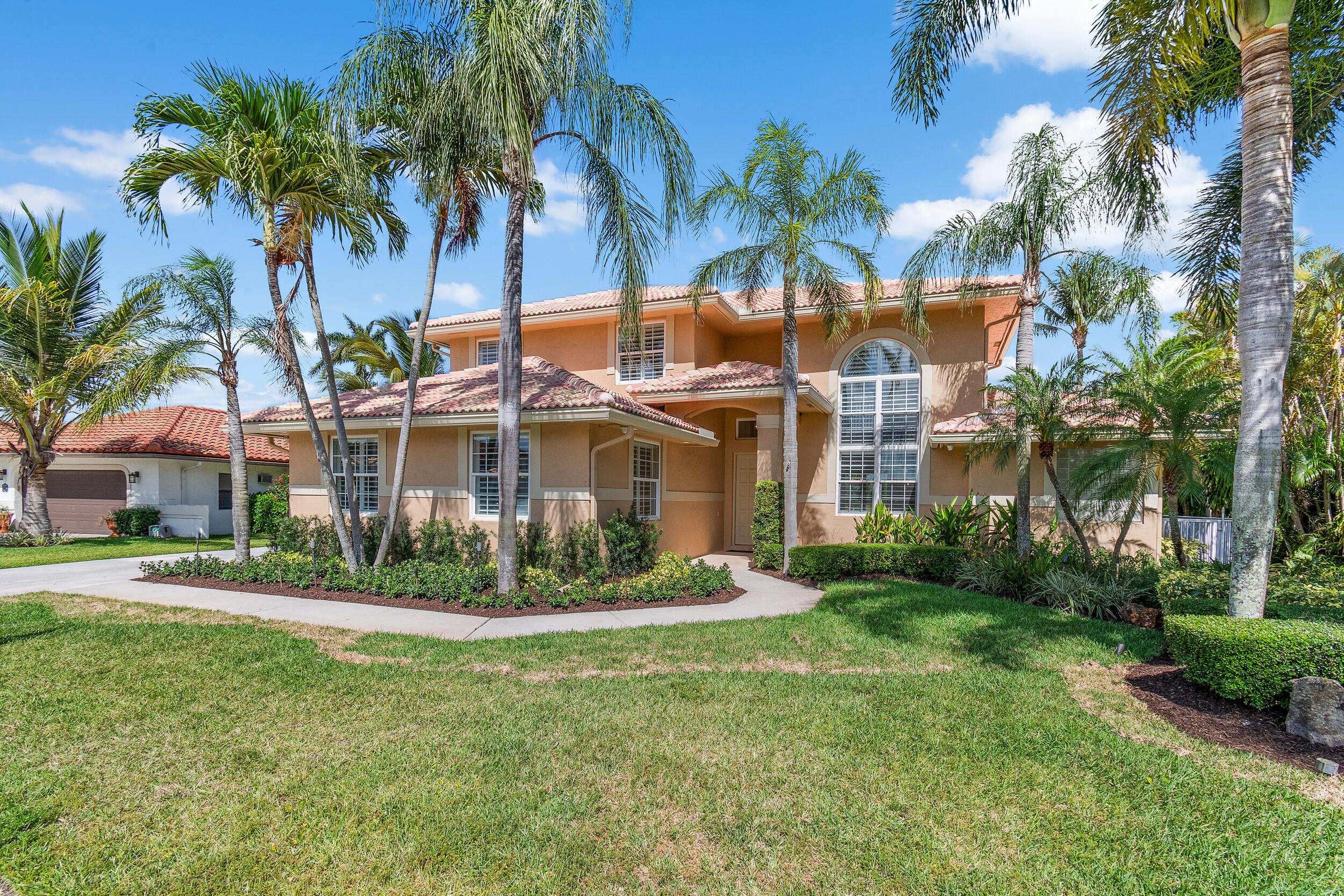 a view of a white house with a big yard and palm trees