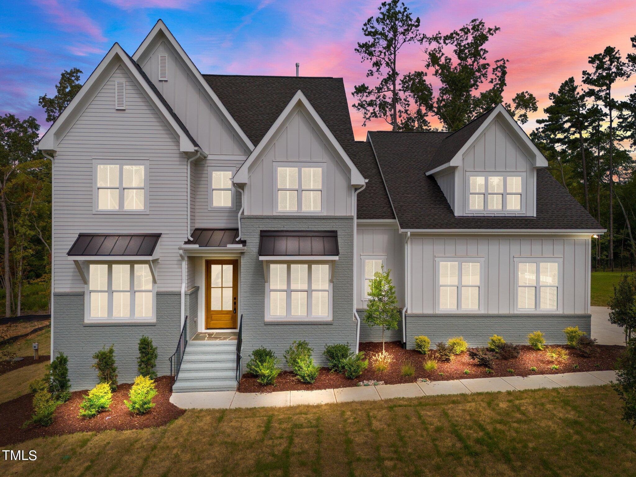 a front view of a house with a yard and potted plants