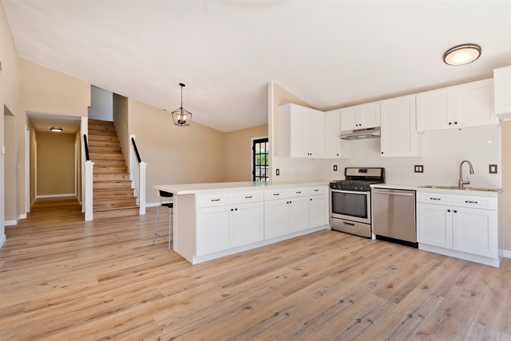 a kitchen with granite countertop a sink cabinets and wooden floor