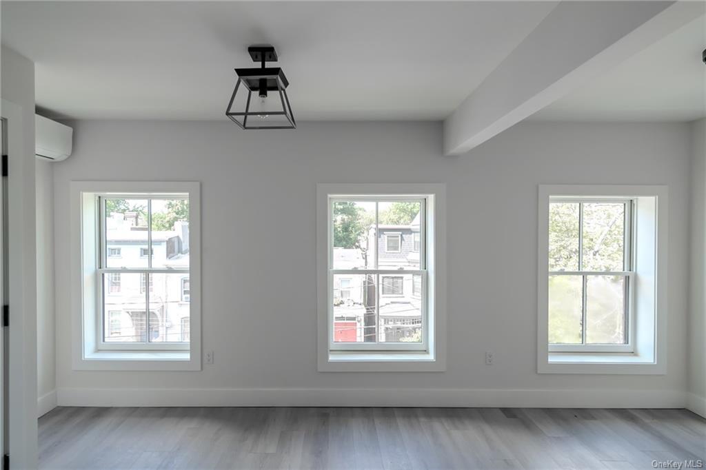 a view of an empty room with wooden floor and windows