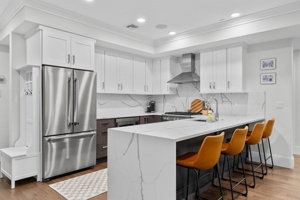 a kitchen with stainless steel appliances a refrigerator a stove a sink and white cabinets