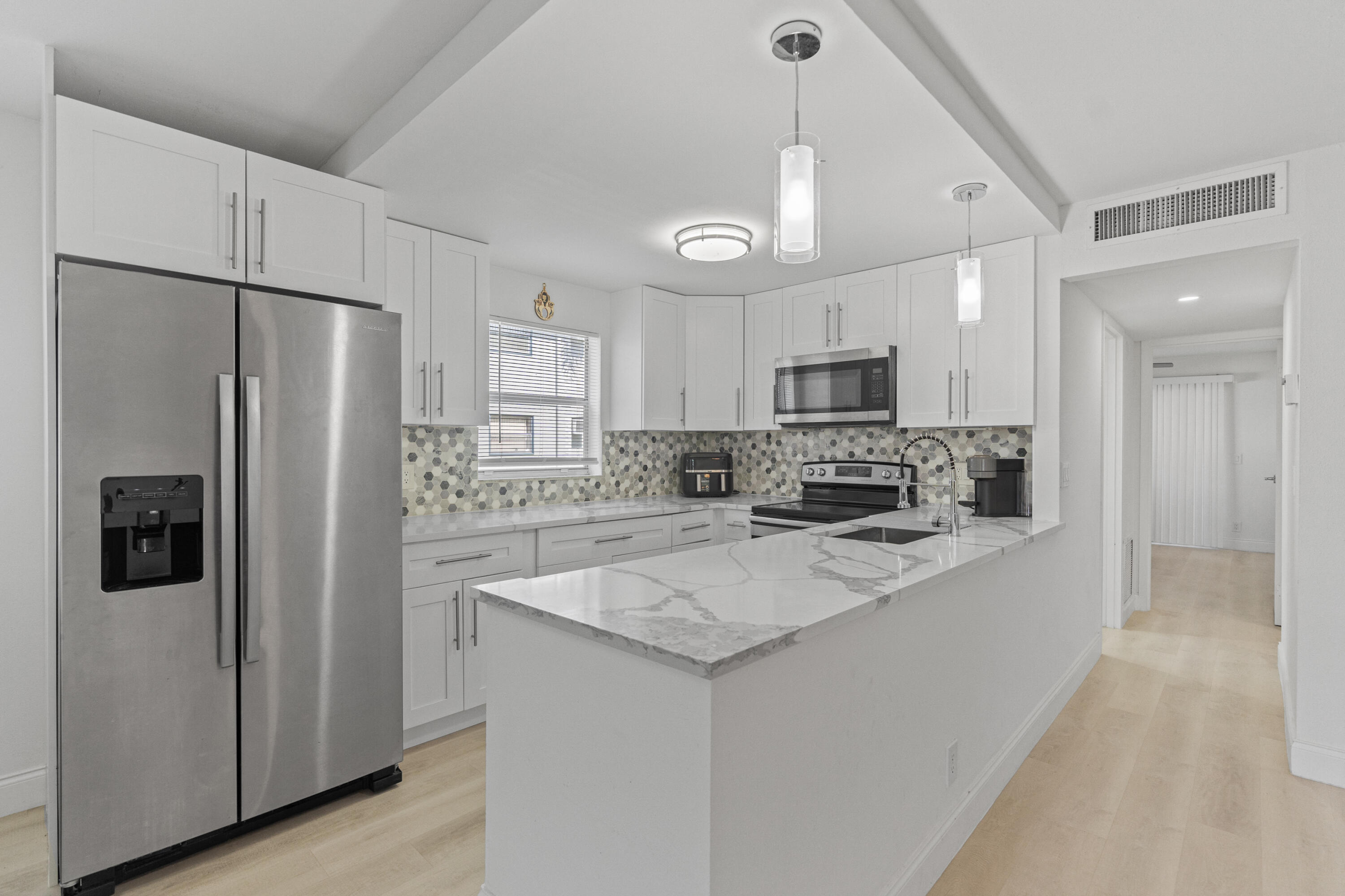 a large kitchen with a refrigerator a sink stainless steel appliances and cabinets