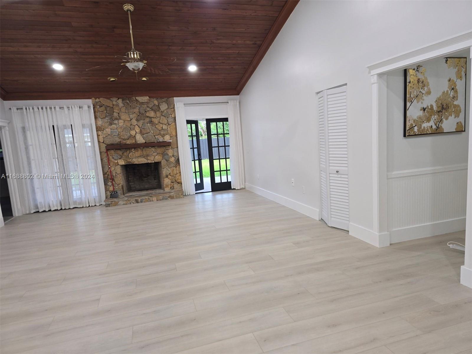 a view of an empty room with wooden floor fireplace and a window