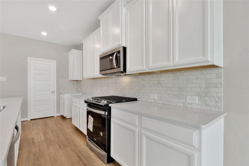 a kitchen with granite countertop white cabinets and black appliances