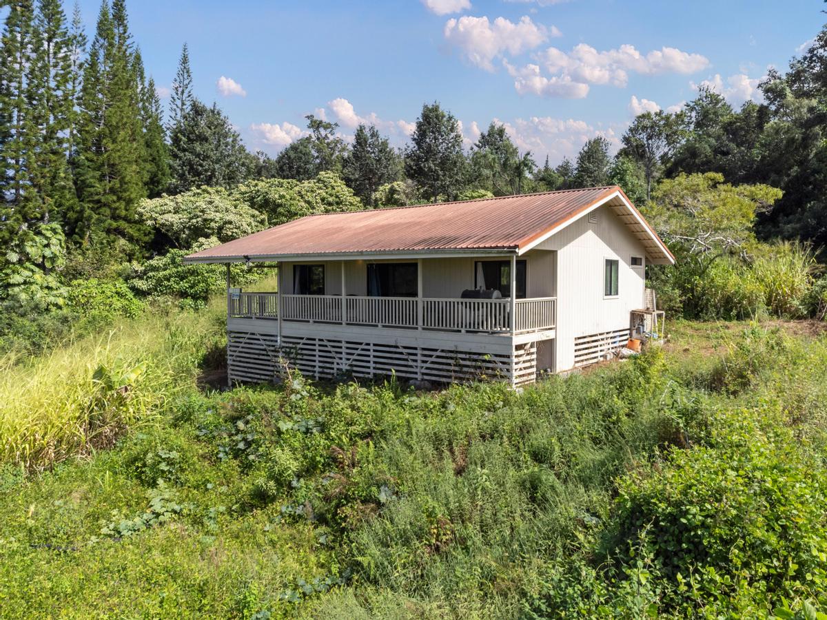 a aerial view of a house with yard and trees in the background