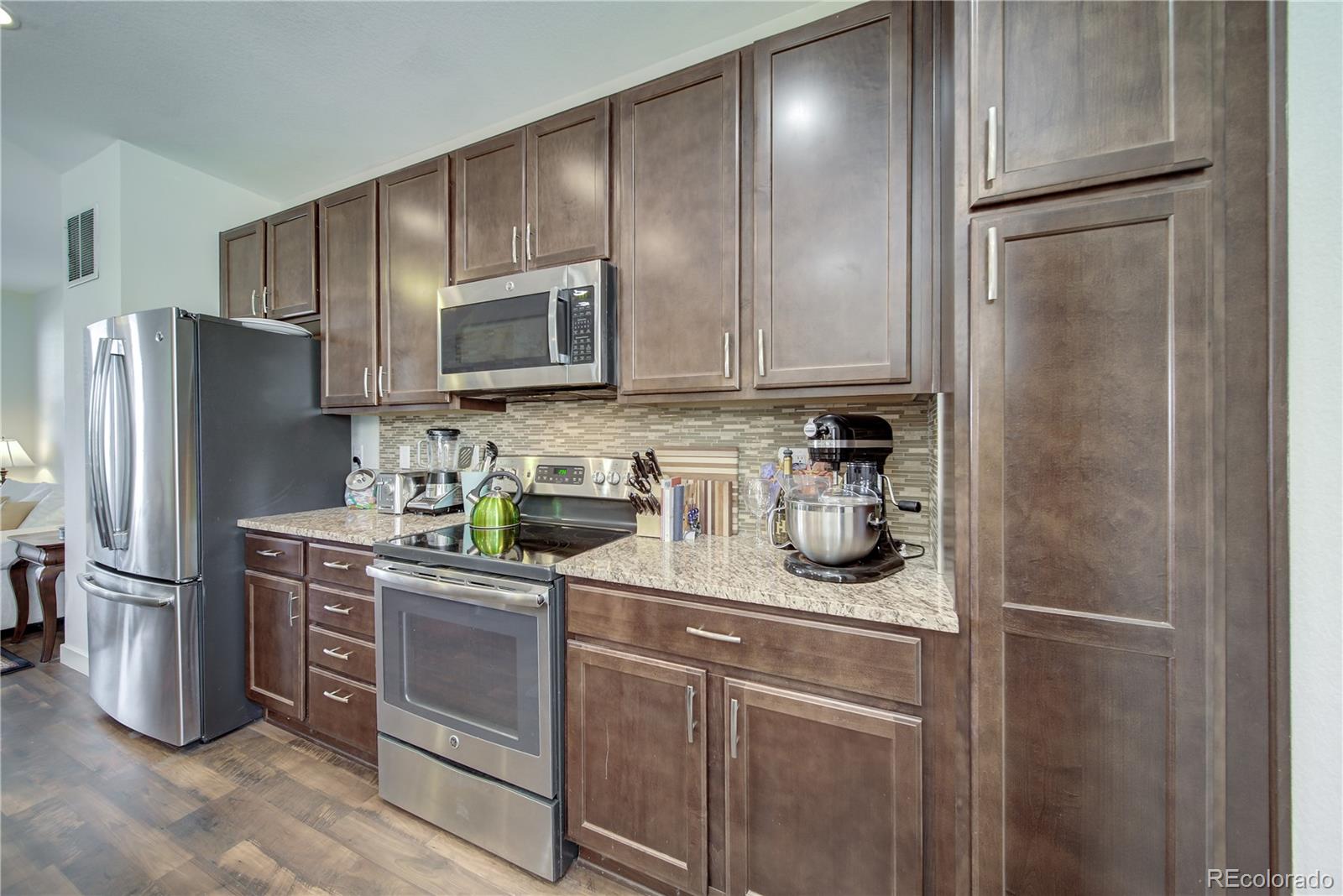 a kitchen with stainless steel appliances granite countertop a refrigerator and a stove top oven