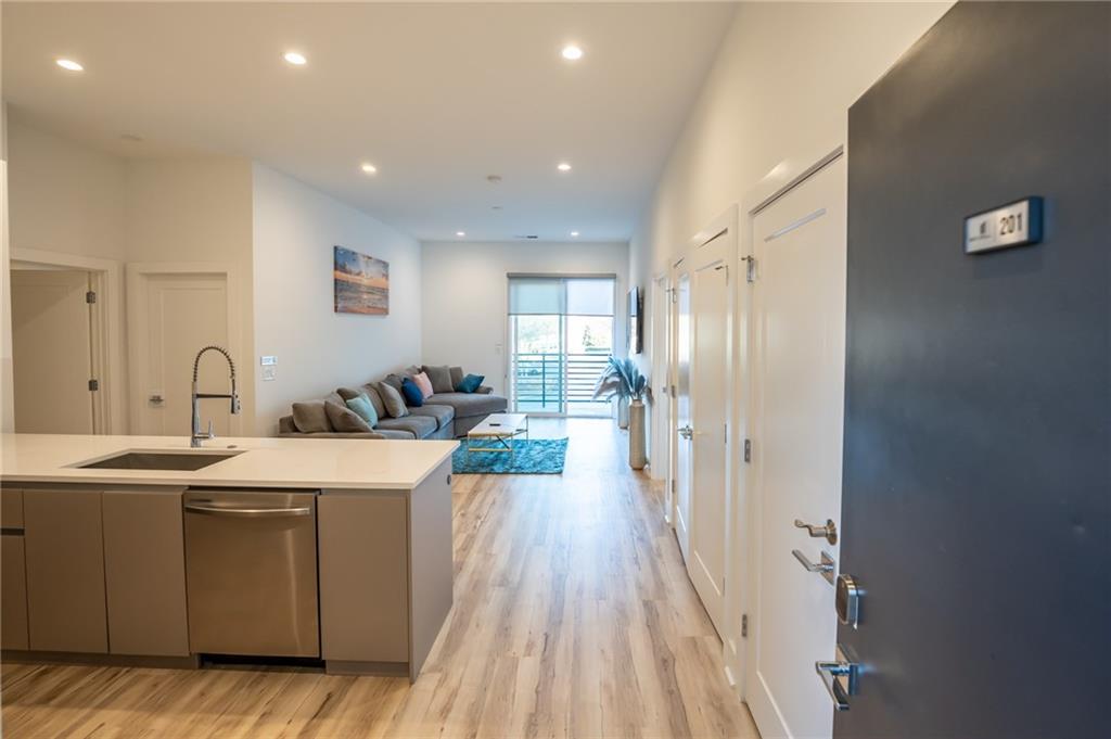 a large kitchen with a sink a counter top space stainless steel appliances and cabinets