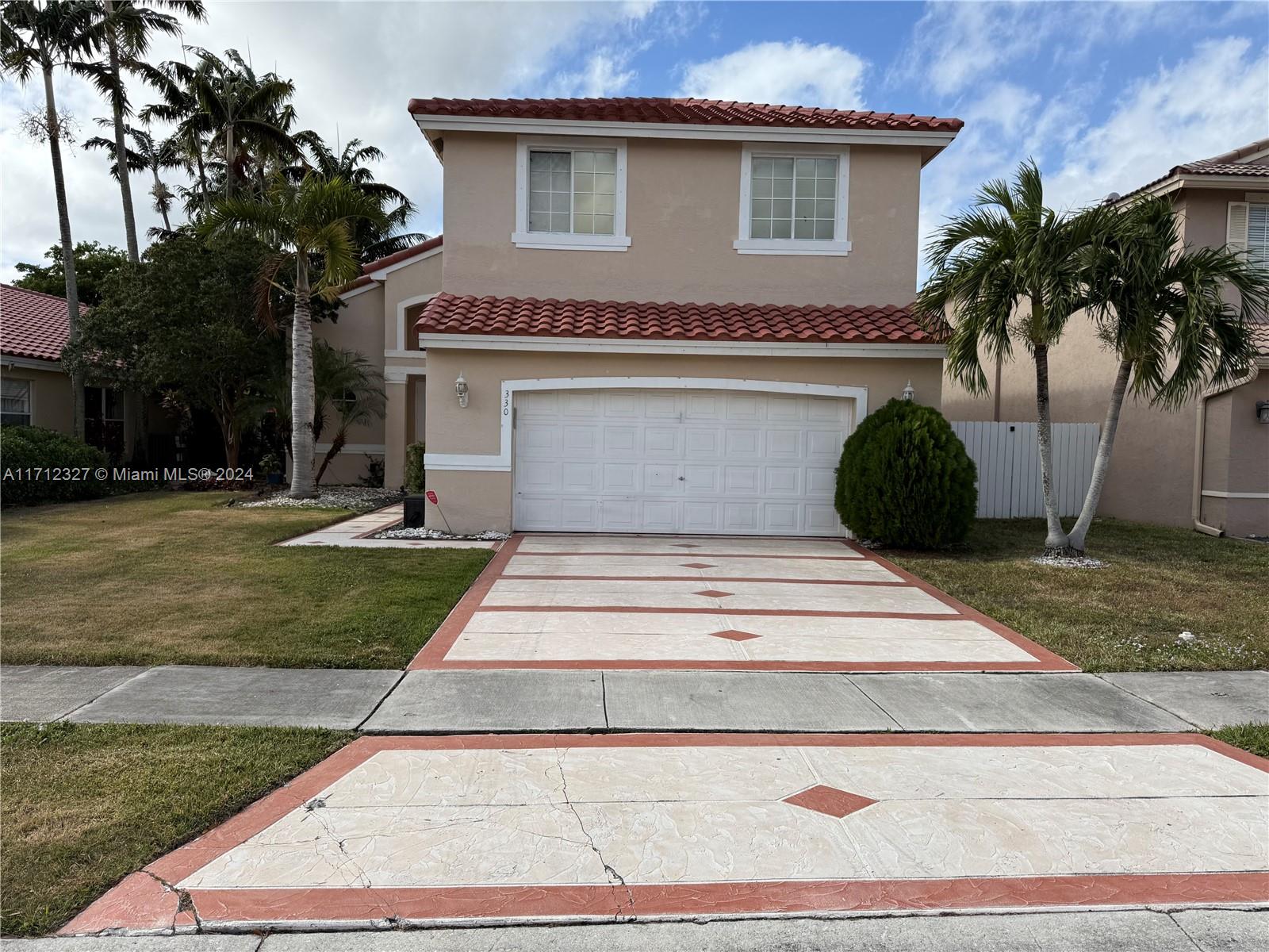 a view of a house with a yard plants and palm trees