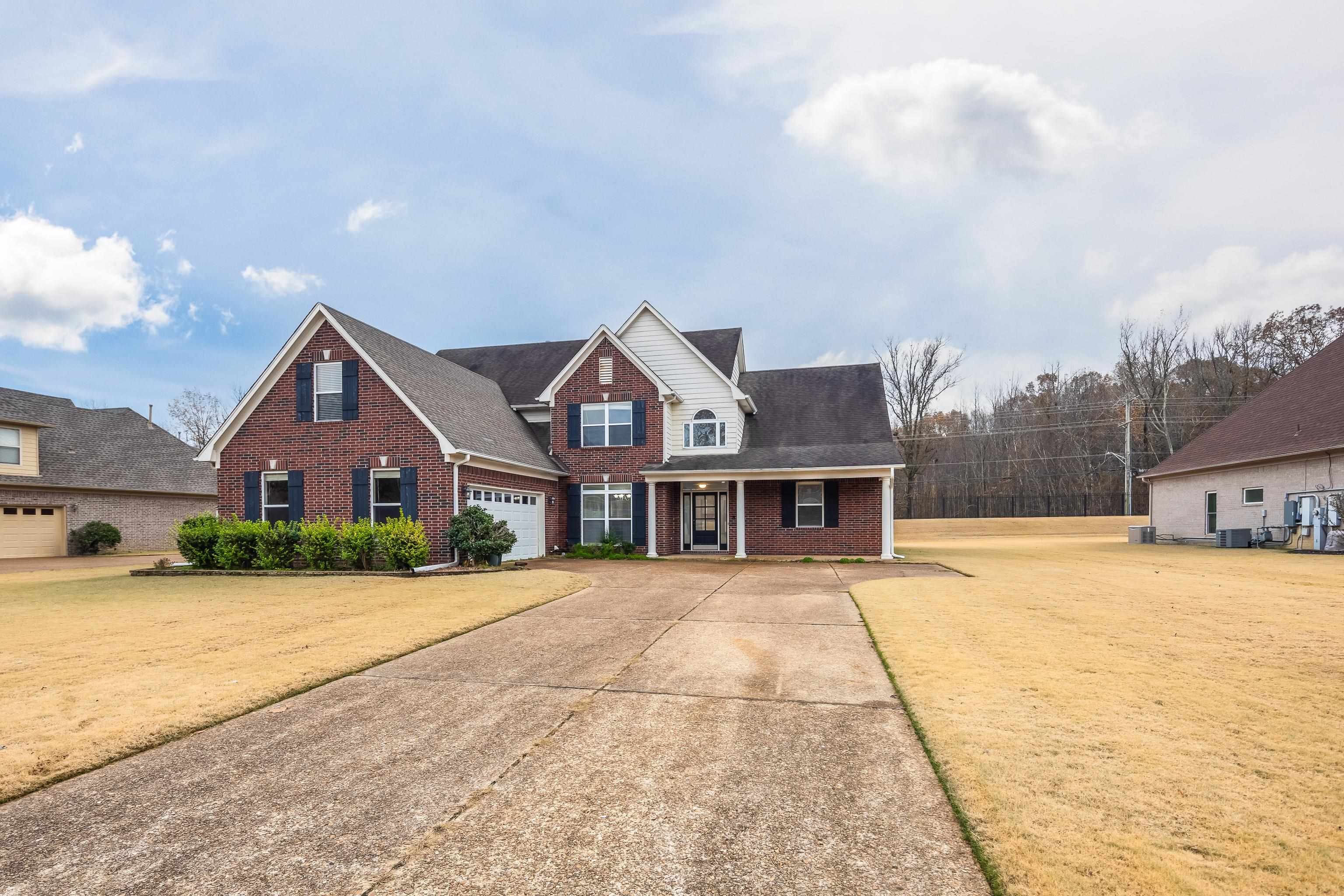 View of front of house featuring a front lawn, covered porch, and a garage