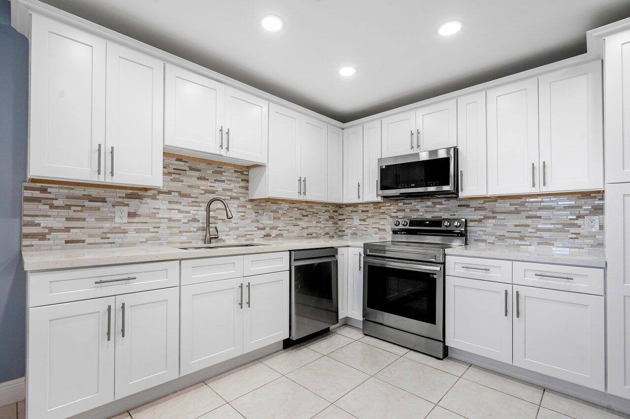 a kitchen with white cabinets stainless steel appliances and sink