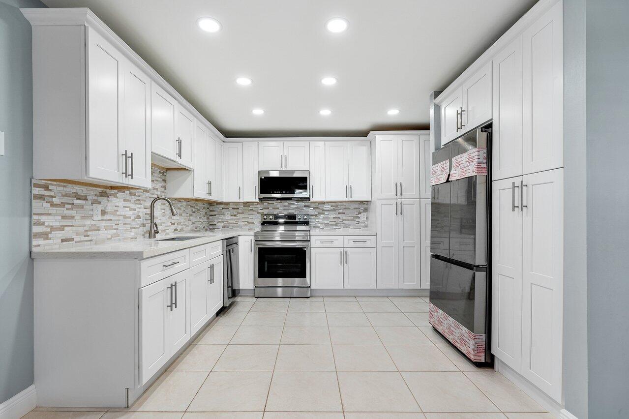 a kitchen with granite countertop a refrigerator and a stove top oven