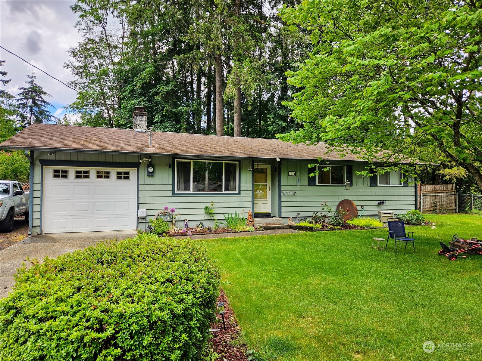 a front view of a house with a garden and trees