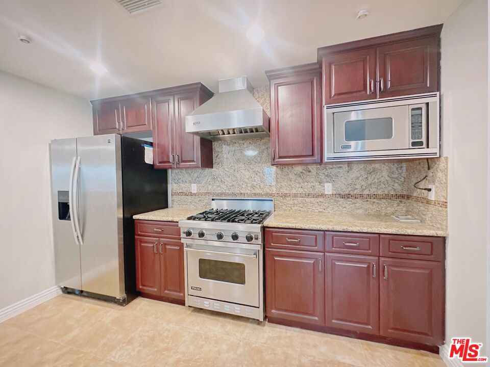 a kitchen with stainless steel appliances granite countertop a stove a refrigerator and a sink