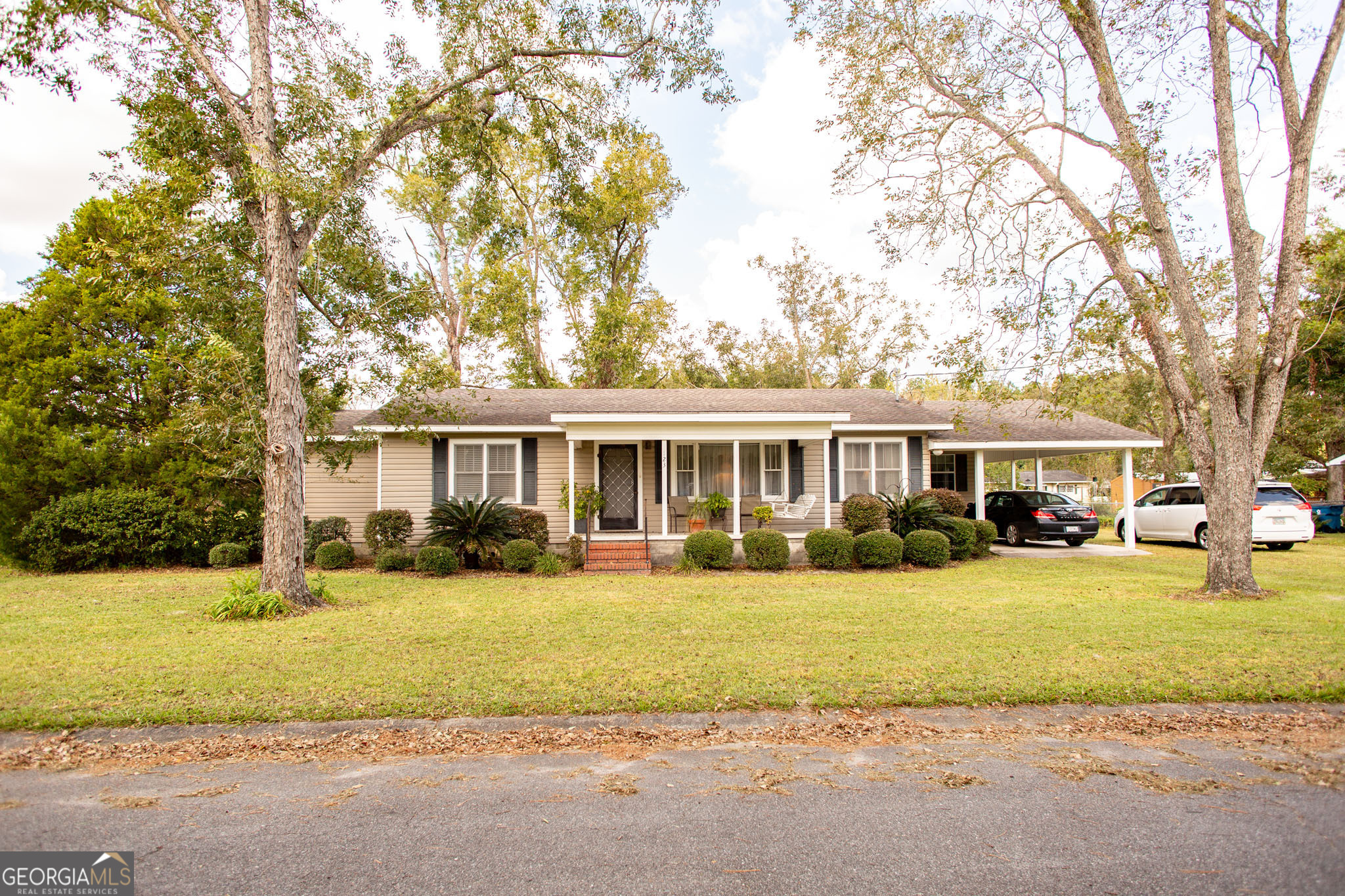 a view of a house with a big yard and large trees