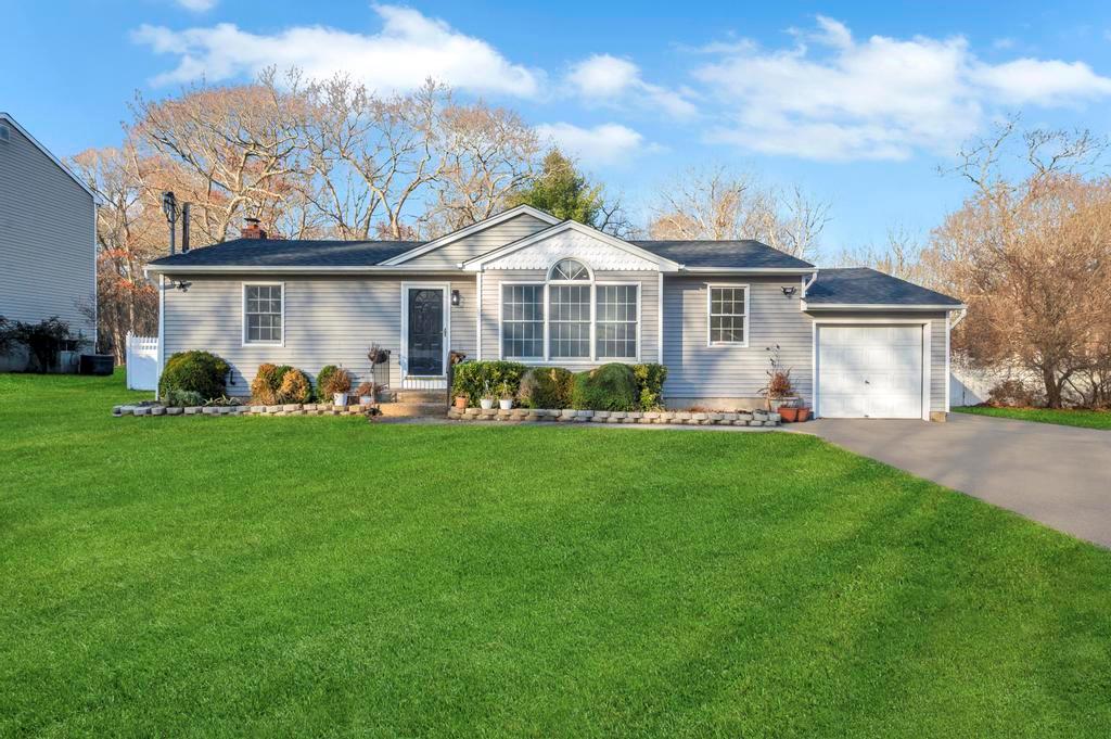 Ranch-style house featuring a garage and a front yard