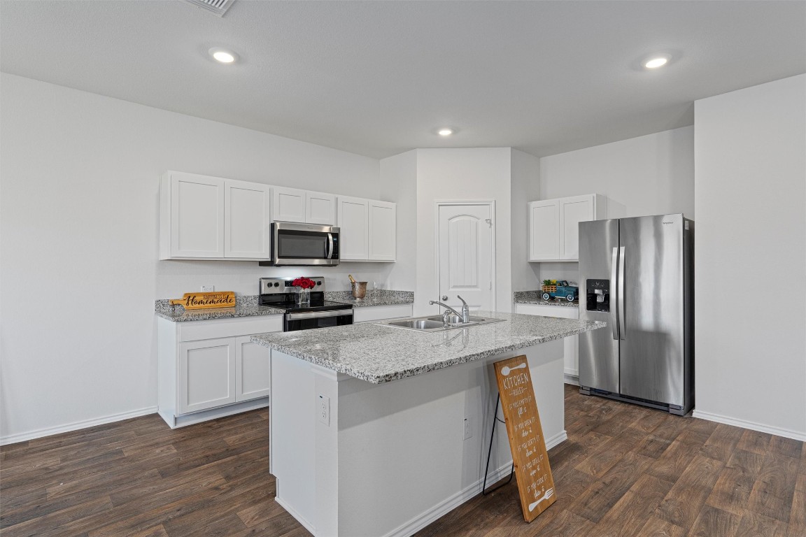 a kitchen with a refrigerator a microwave a stove and wooden floor