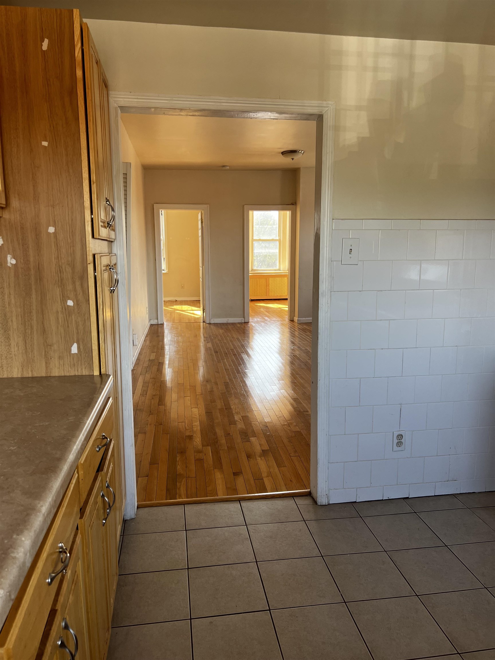 a view of a hallway with wooden floor and a bathroom