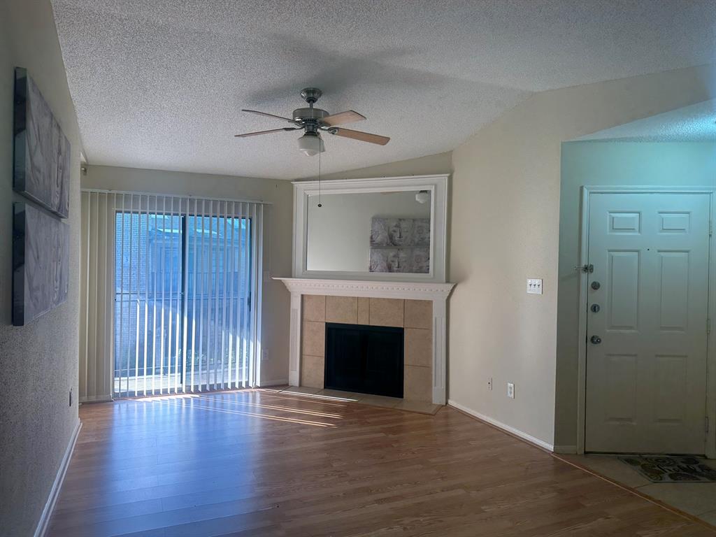 a view of an empty room with wooden floor and a fireplace