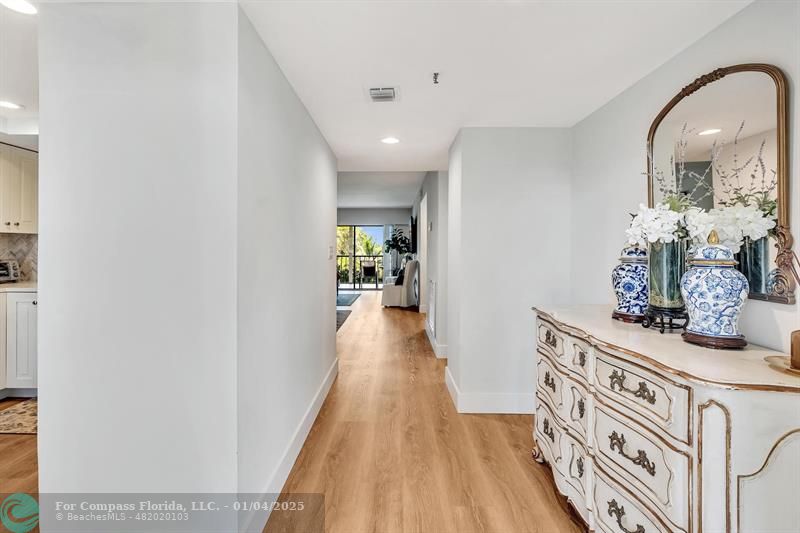 a view of a hallway with wooden floor and furniture