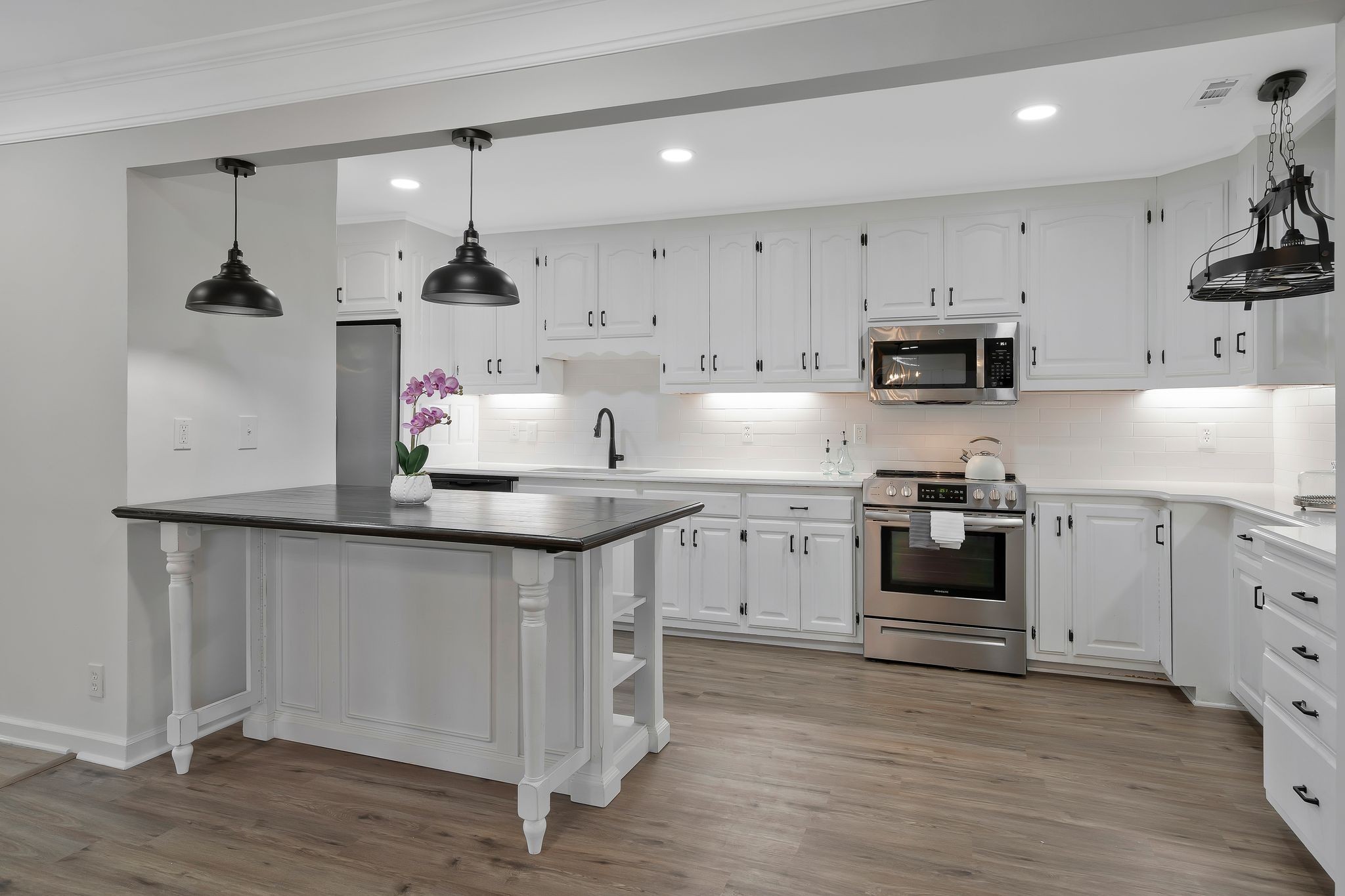 a kitchen with kitchen island a white counter top space cabinets and stainless steel appliances