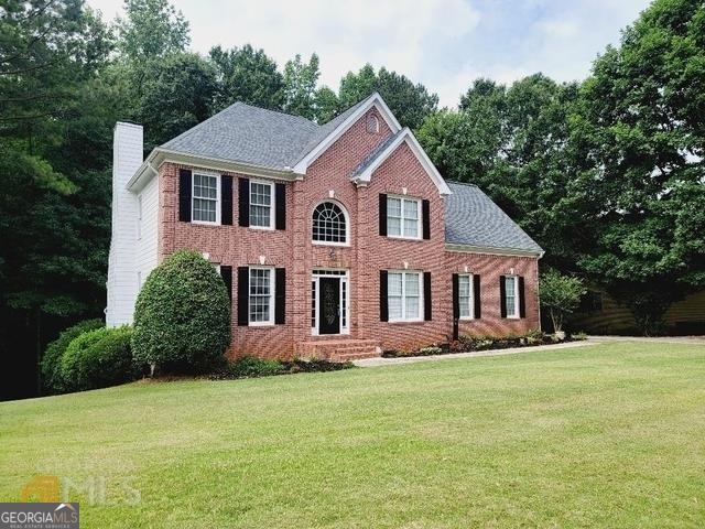 a front view of a house with a yard and trees