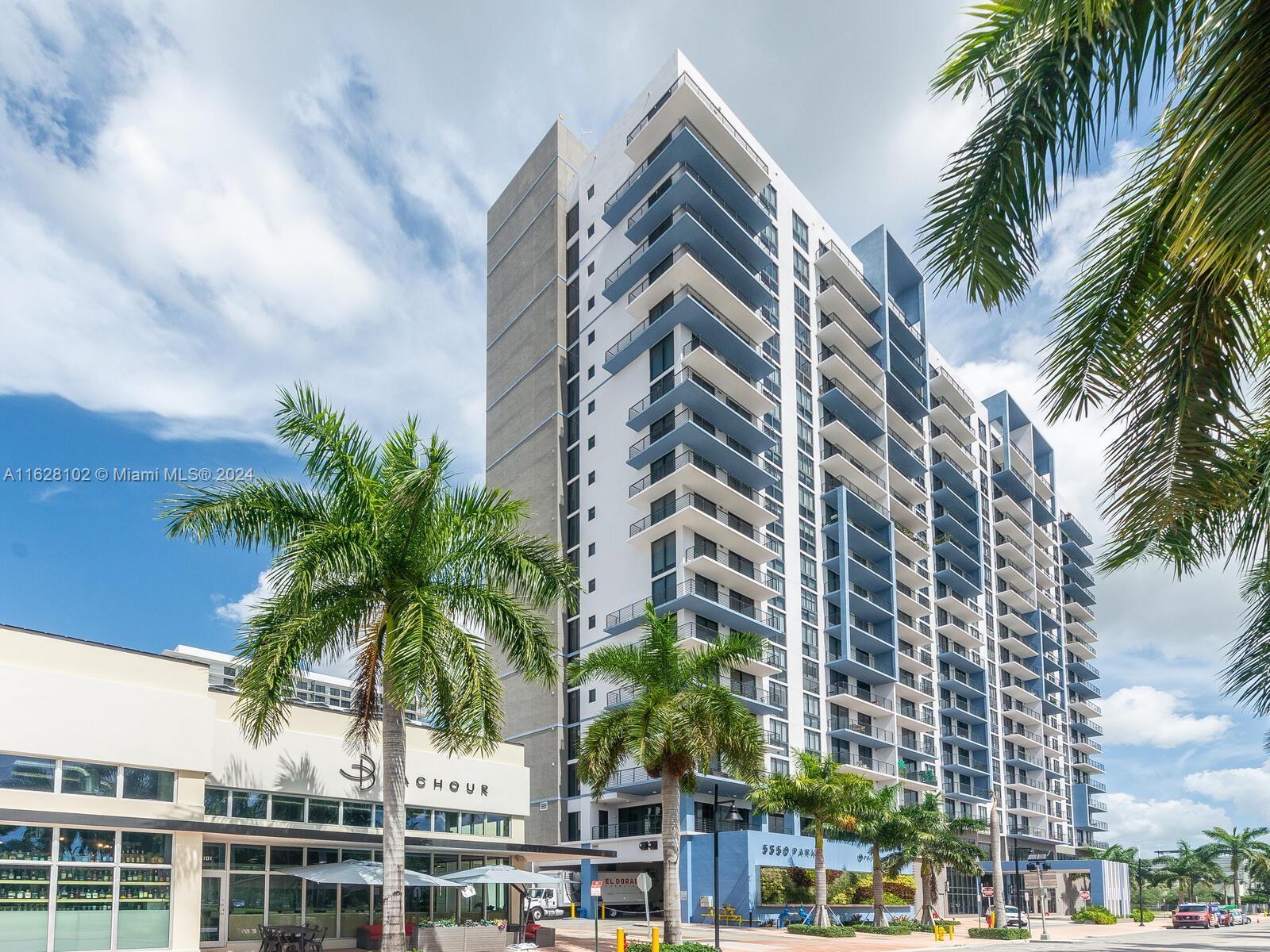 a front view of multi story residential apartment building with yard and parking space