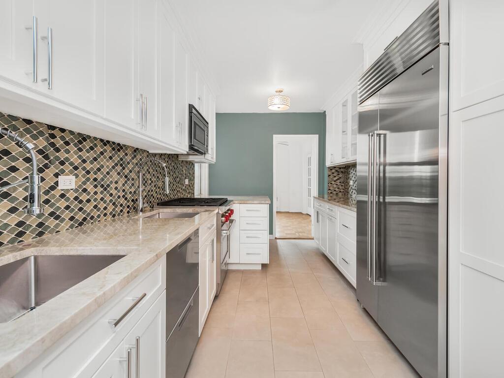 Kitchen featuring light stone counters, white cabinets, dishwasher, and built in fridge