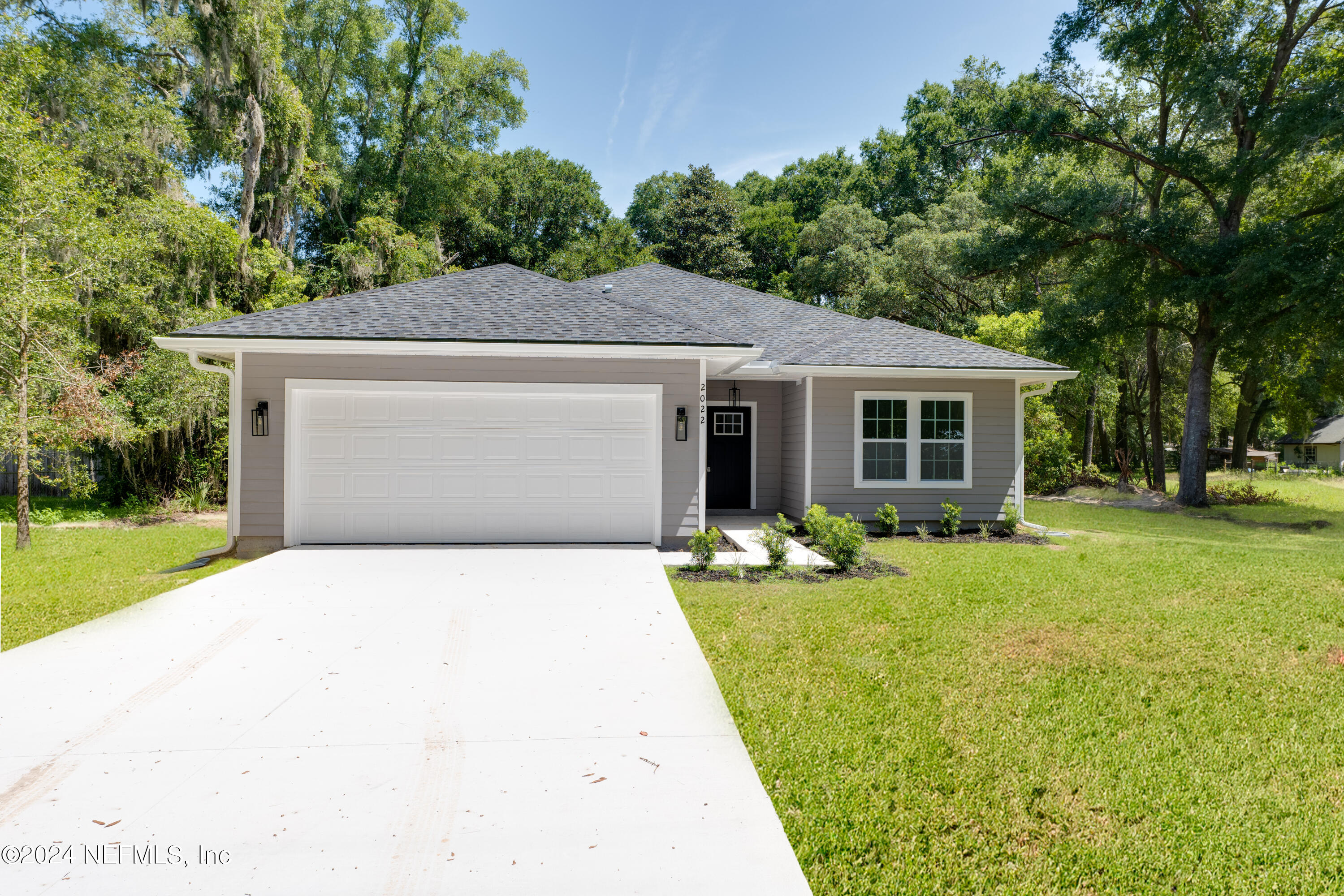 a front view of a house with a yard garage and trees