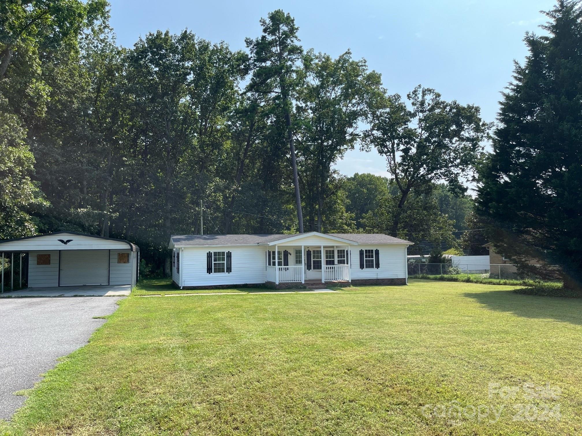 a view of a house with a big yard and large trees