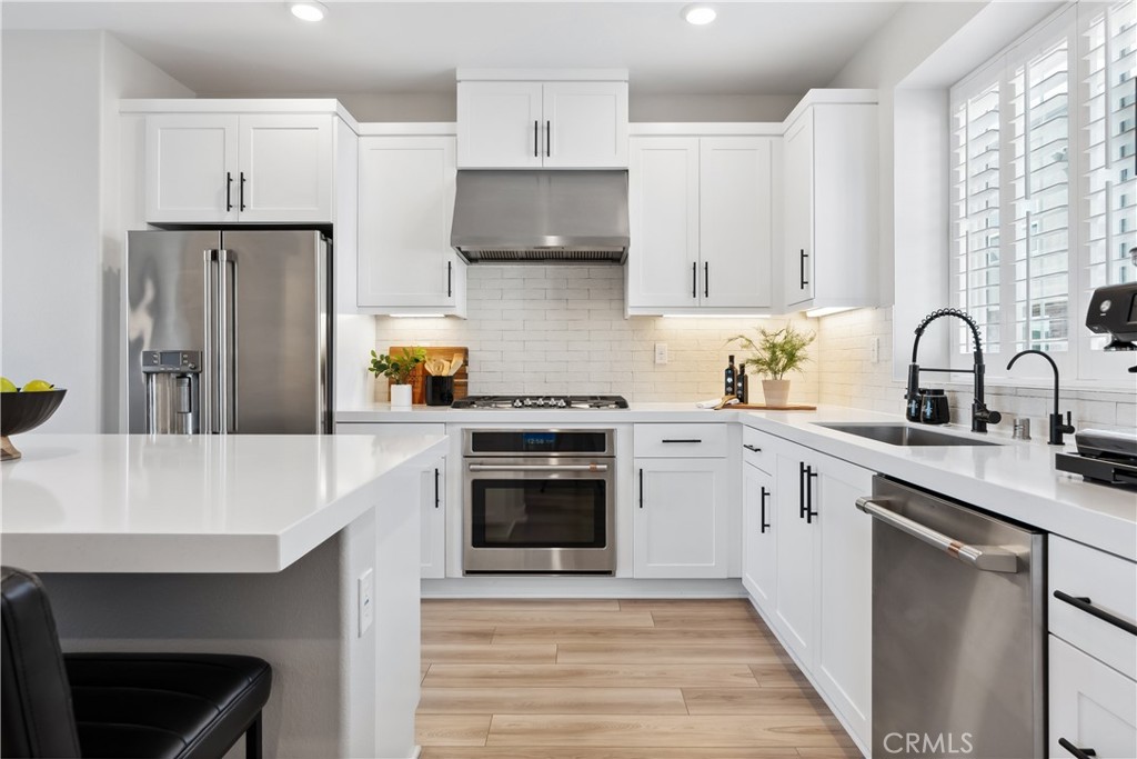 a kitchen with stainless steel appliances white cabinets a sink and a stove