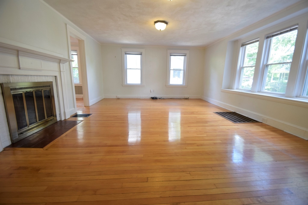 a view of an empty room with window and fireplace