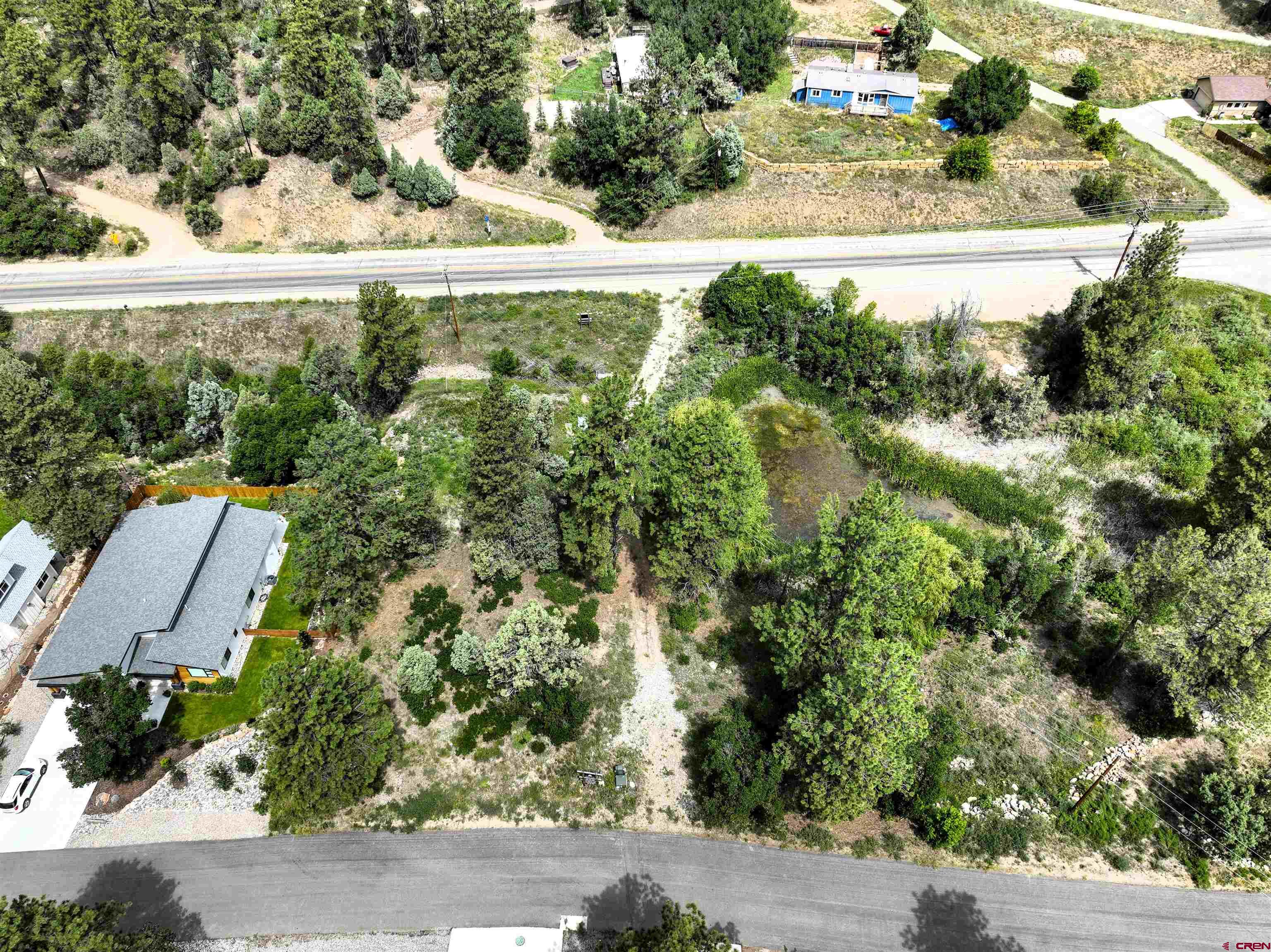 an aerial view of residential houses with outdoor space and trees all around