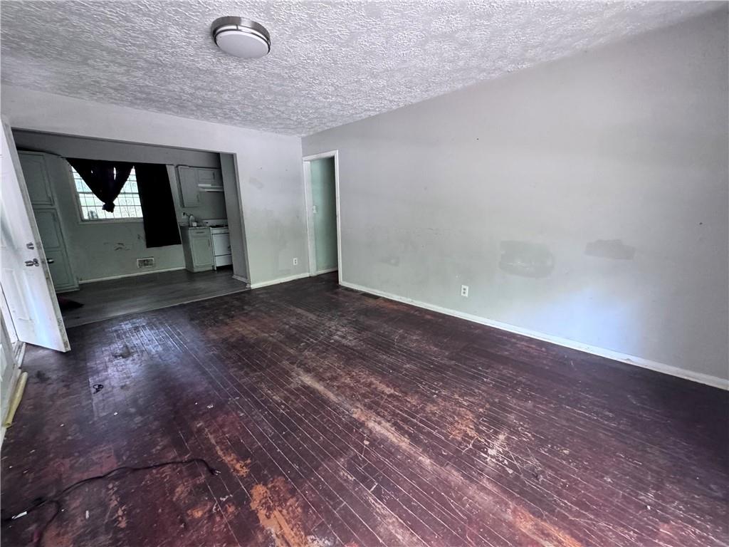 a view of an empty room with wooden floor and closet