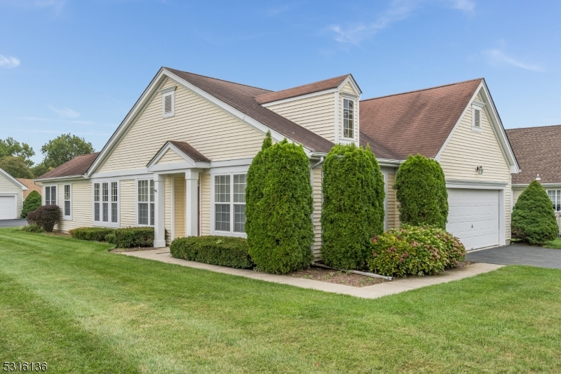 a view of a house in front of a big yard plants and large trees