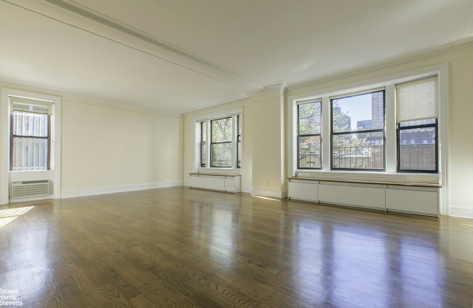 a view of an empty room with wooden floor and windows