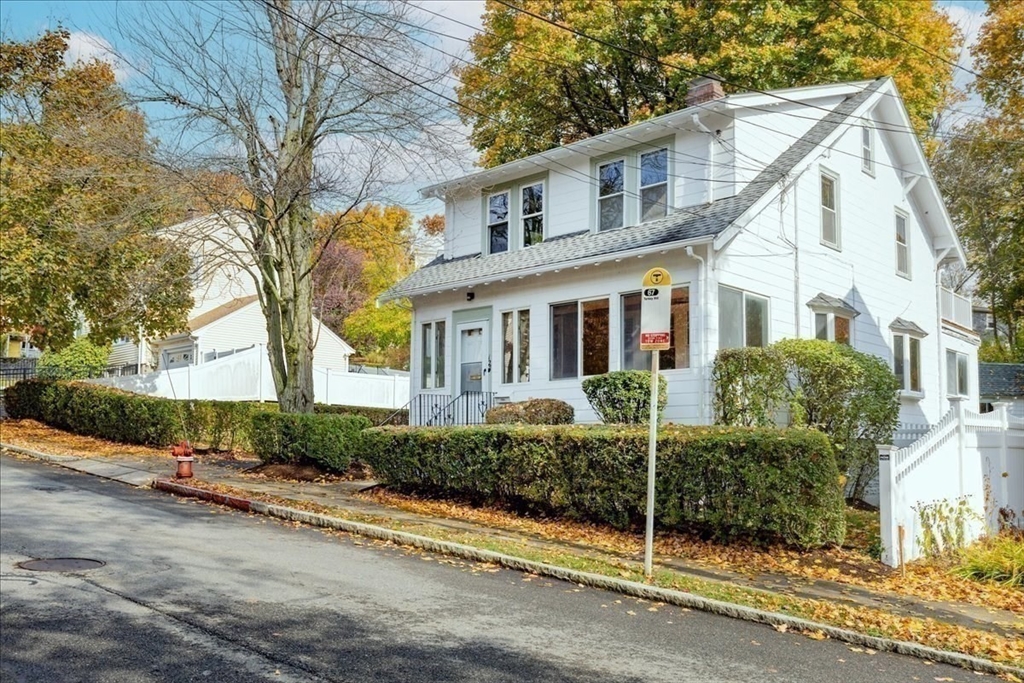 a view of a white house next to a road and yard