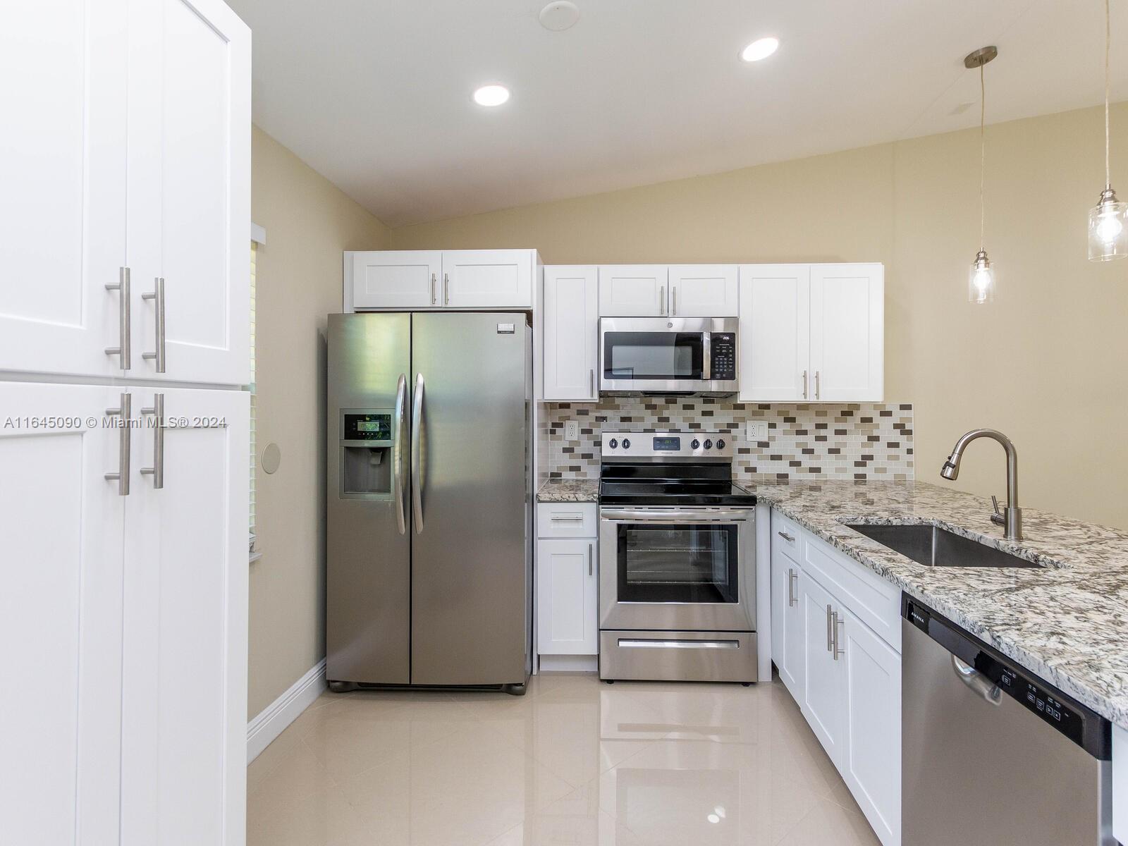 a kitchen with stainless steel appliances granite countertop a refrigerator and a stove top oven