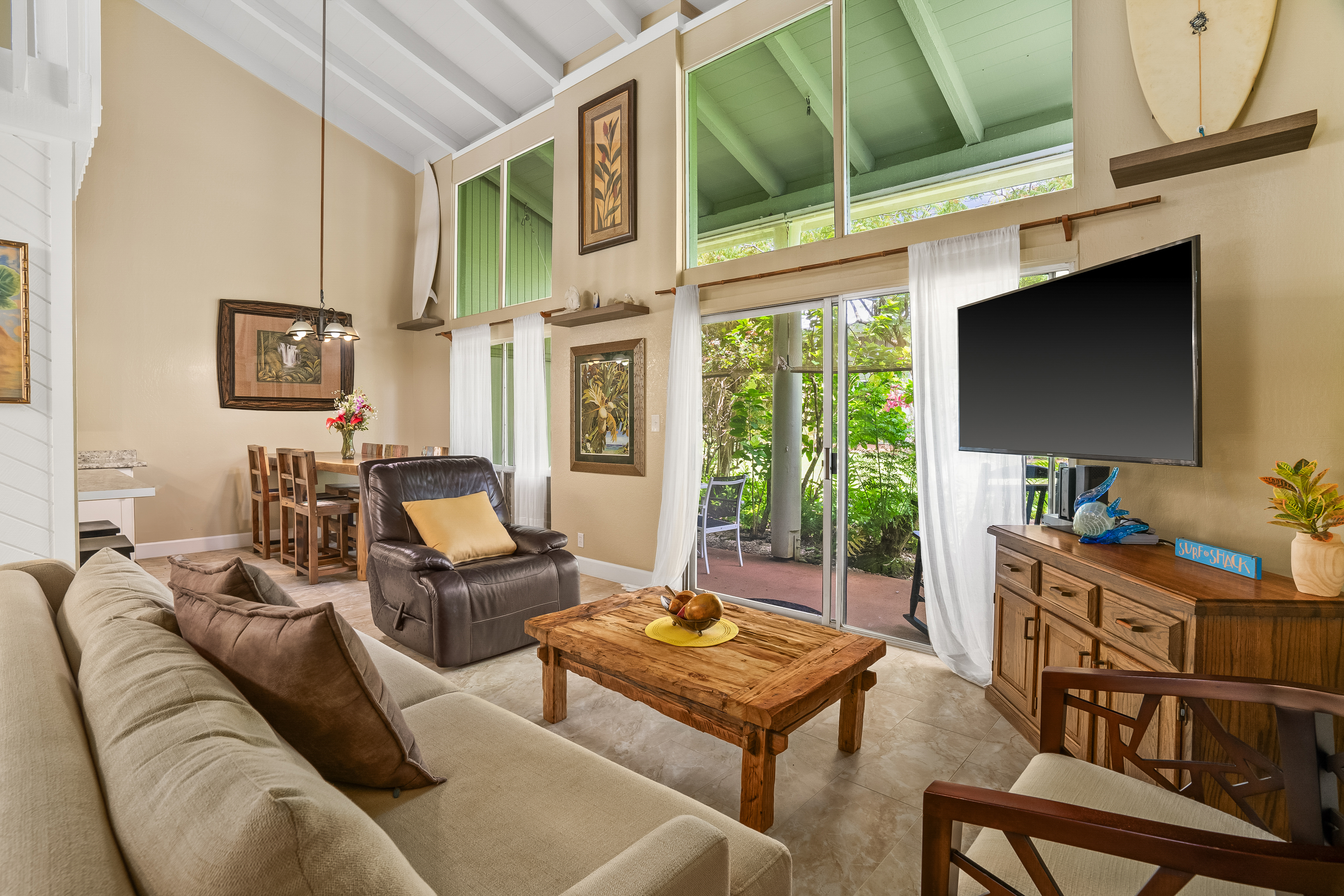 a living room with furniture a flat screen tv and a floor to ceiling window