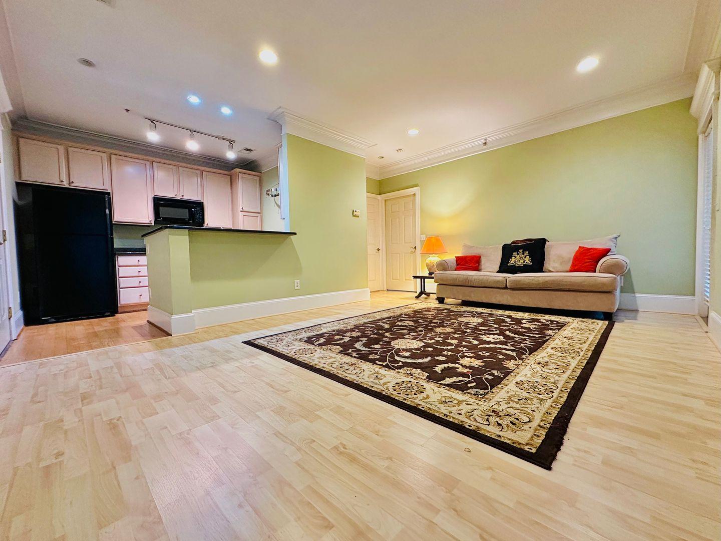 a living room with stainless steel appliances furniture and a wooden floor