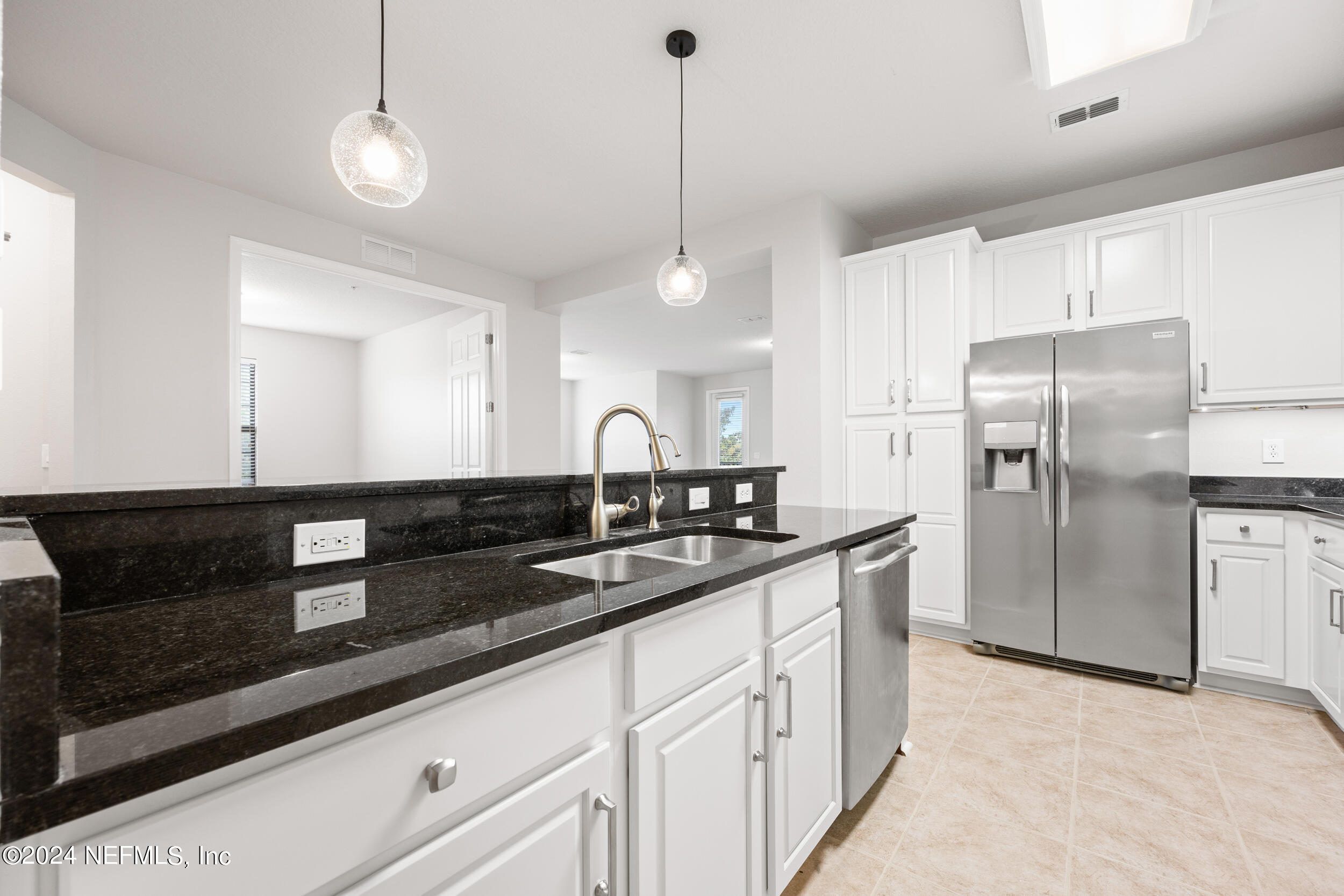 a kitchen with granite countertop a refrigerator a sink and cabinets