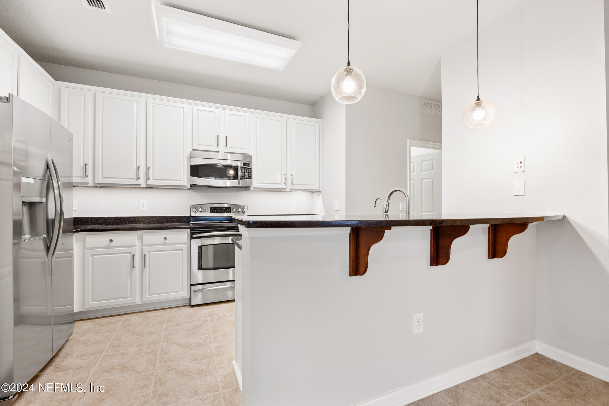 a kitchen with granite countertop white cabinets and stainless steel appliances