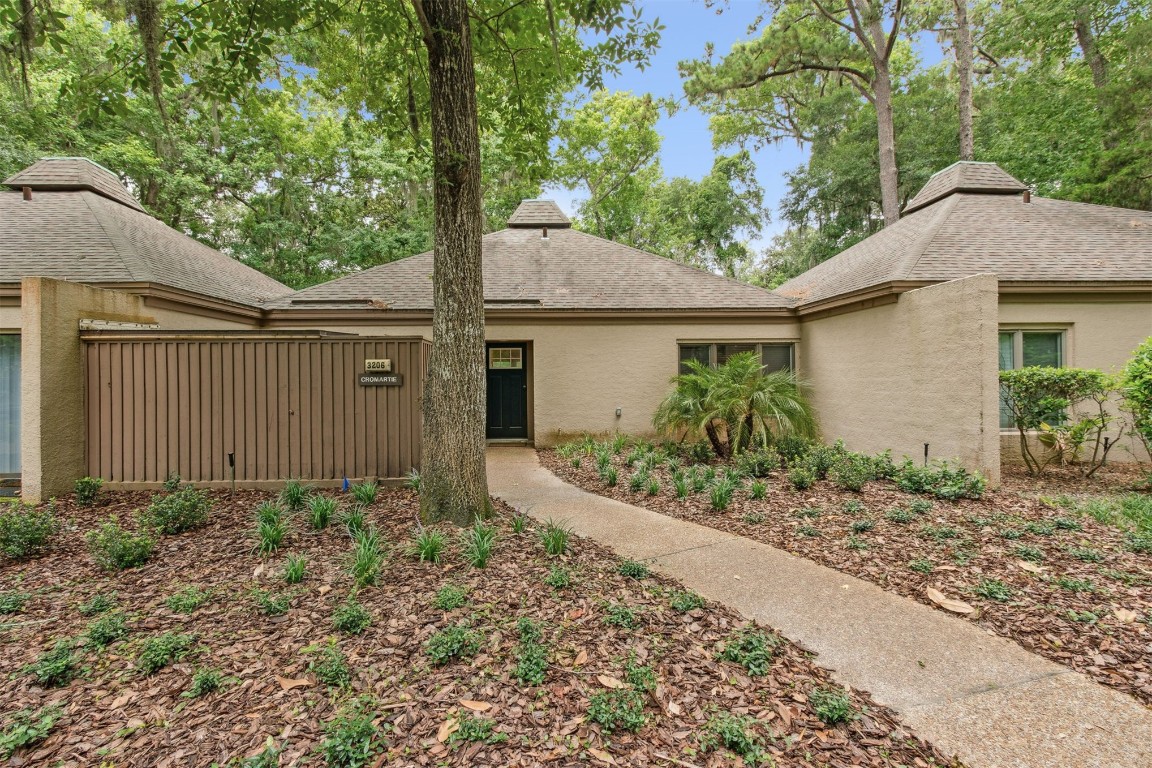 a view of a house with a small yard plants and large tree