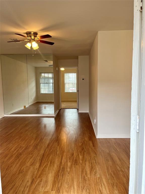 a view of an empty room with window and wooden floor