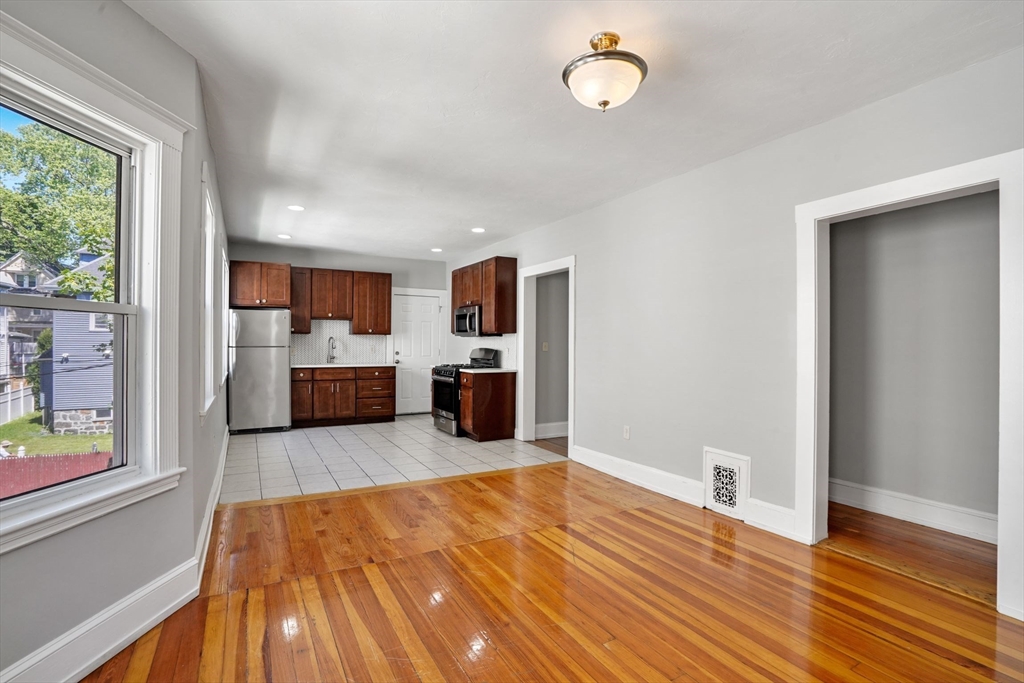 a large room with wooden floor and a kitchen