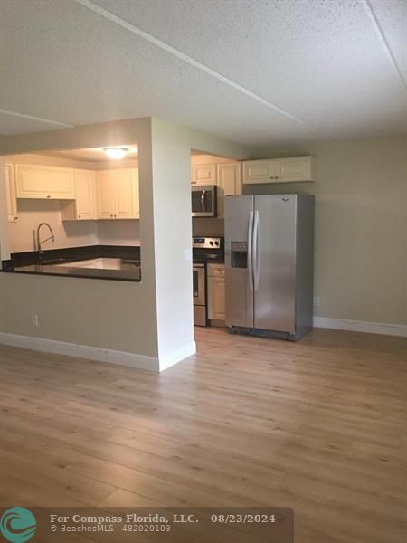 a view of a refrigerator in kitchen and an empty room