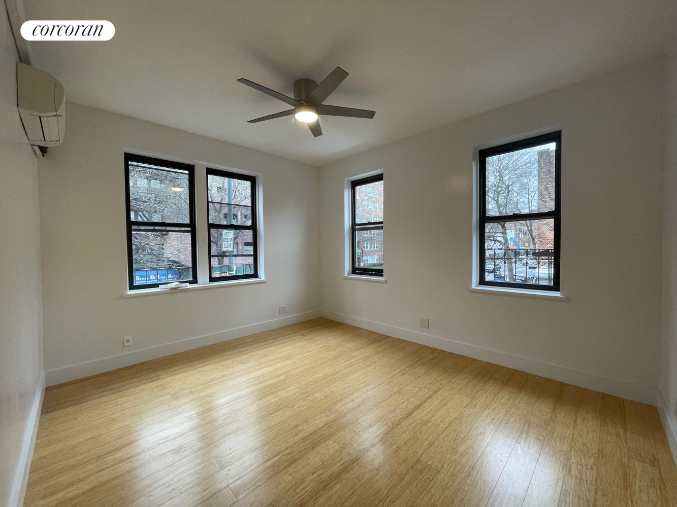 a view of an empty room with window and wooden floor