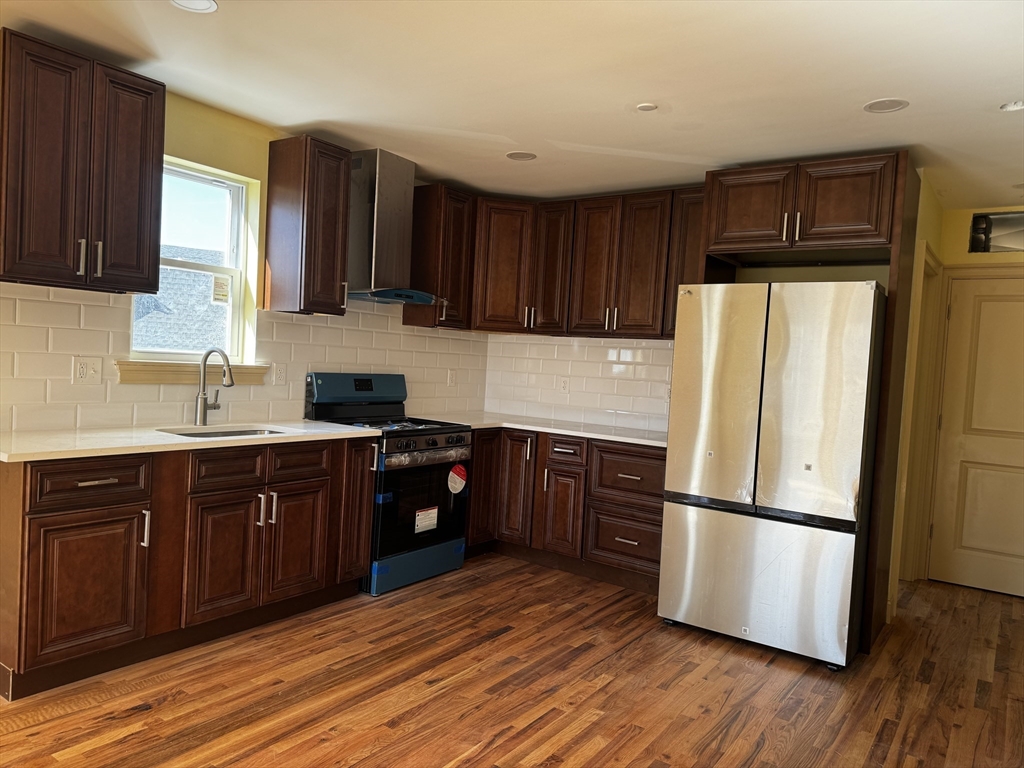 a kitchen with granite countertop wooden floors stainless steel appliances and cabinets